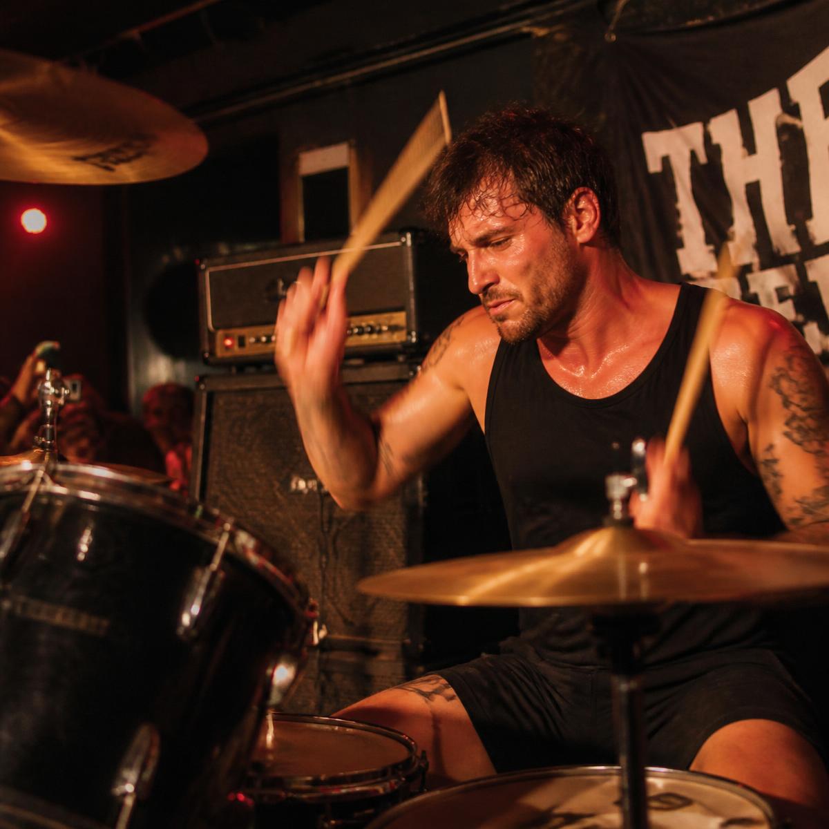 Drummer playing hard in a sweaty club